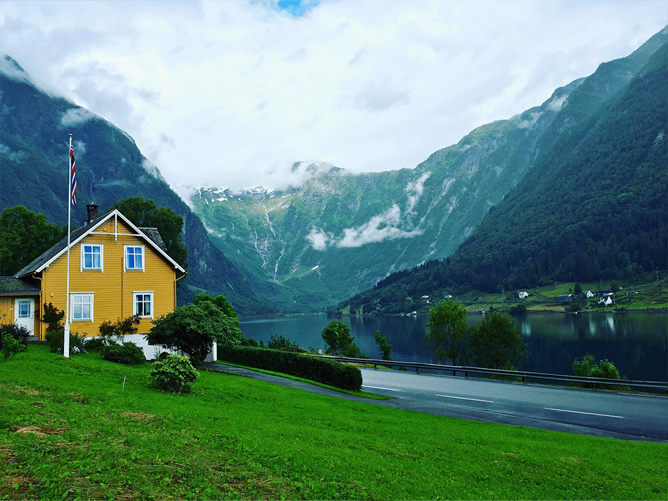 Gult hus med norsk flagg og fjellandskap